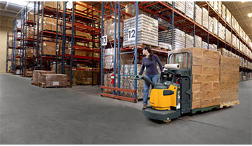 Woman Riding a Jungheinrich End-Rider Pallet Truck through a Warehouse